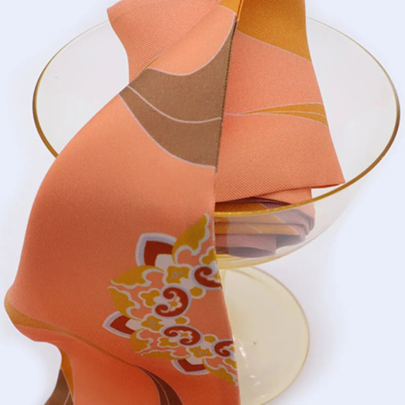 Chinese Dunhuang Motif Print Mulberry Silk Twilly 160x7.3 cm styled on a glass stand, showing the orange motif print and silky drape.