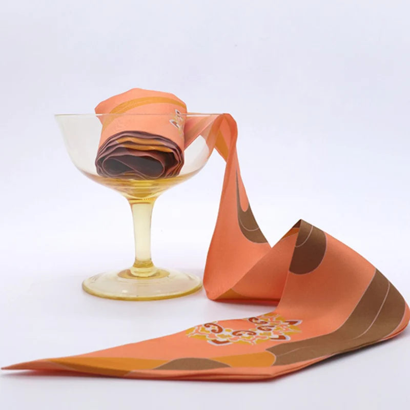 Chinese Dunhuang Motif Print Mulberry Silk Twilly 160x7.3 cm styled beside a glass display, highlighting its elegant orange Dunhuang pattern.