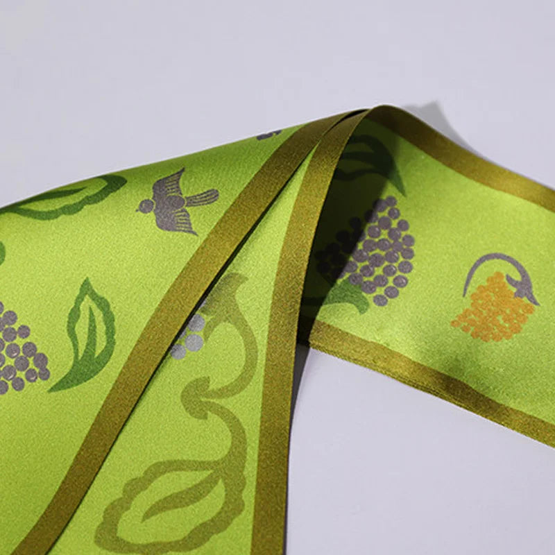 Close-up detail of the Chinese Grape Vine Print Mulberry Silk Twilly, highlighting the green silk texture and printed grape vine pattern.