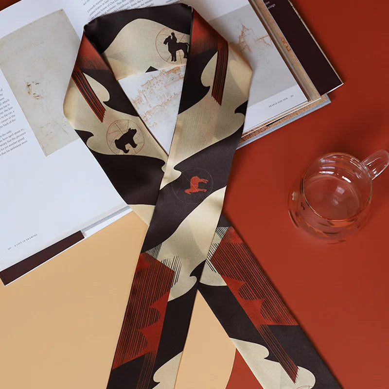 Styled flat lay of Chinese Han Dynasty Painted Pottery Motif mulberry silk twilly scarf with books and glassware.