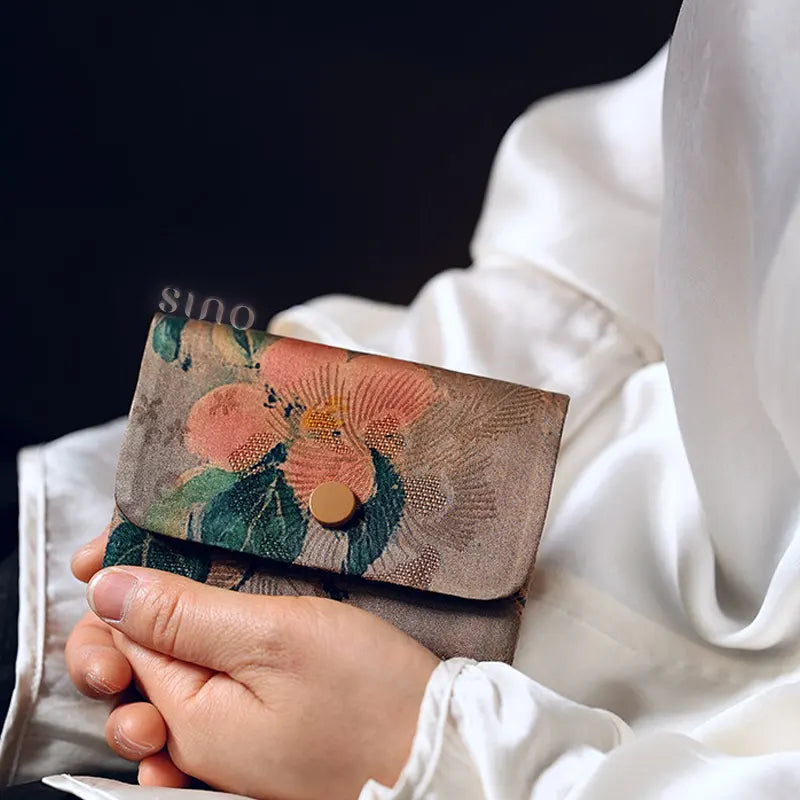 Handheld lifestyle view of the Chinese Xiangyunsha Silk Camel Floral Snap Card Holder Wallet, highlighting its compact shape and traditional floral textile design.