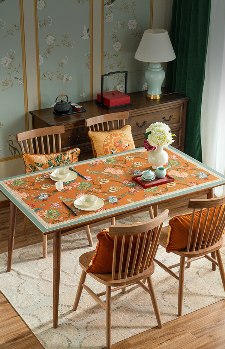 Chinoiserie floral tablecloth on wooden dining table with teaware and decorative wall art.