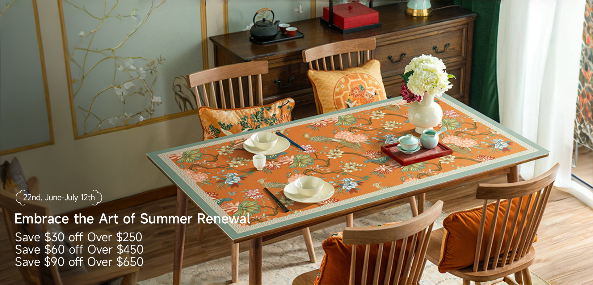 Chinoiserie floral tablecloth on wooden dining table with teaware and decorative wall art.
