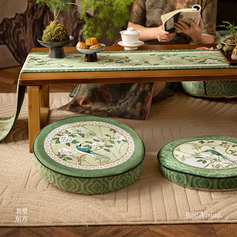 Front view of Style A and B tatami poufs in front of a table, with model reading behind.