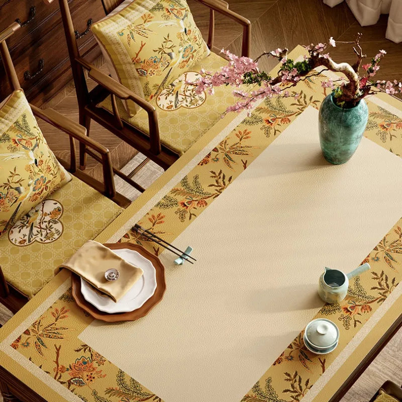 Autumn Splendor leather table mat featuring elegant floral and long-tailed bird motifs in warm golden tones.