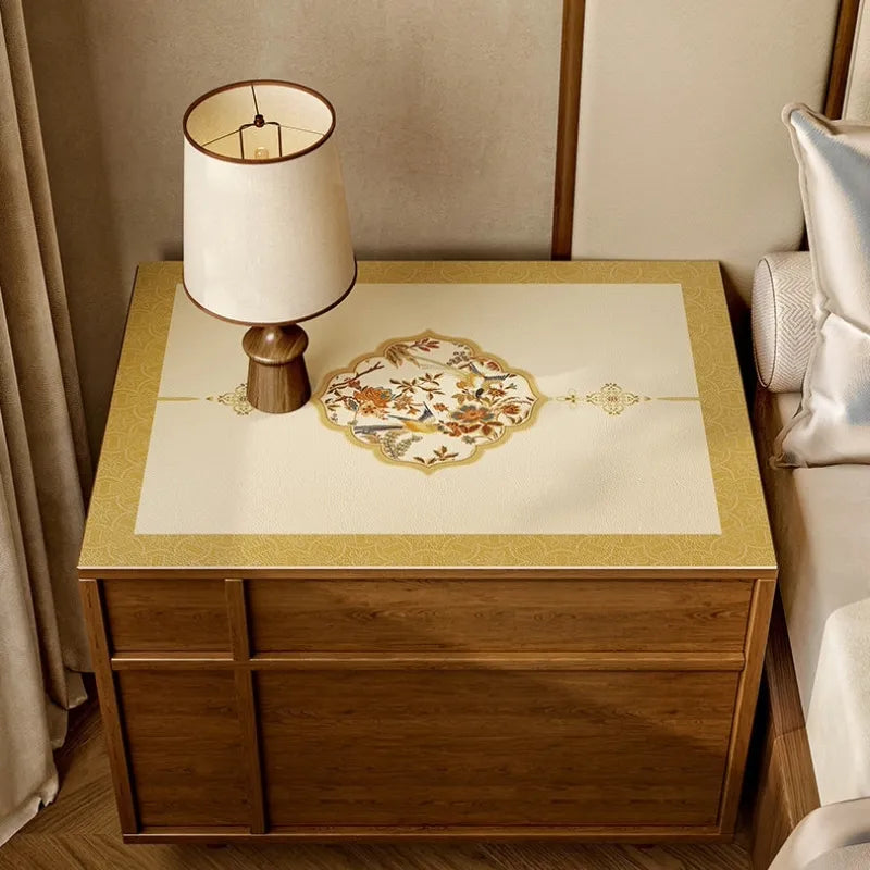 Autumn Splendor ivory and golden leather nightstand mat with elegant floral bird medallion and bedside lamp.