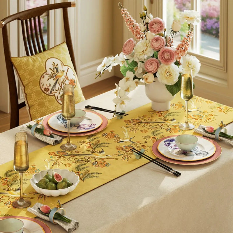 Chinoiserie yellow dining table runner styled with tableware and flowers for an elegant autumn dinner party and seasonal table setting.