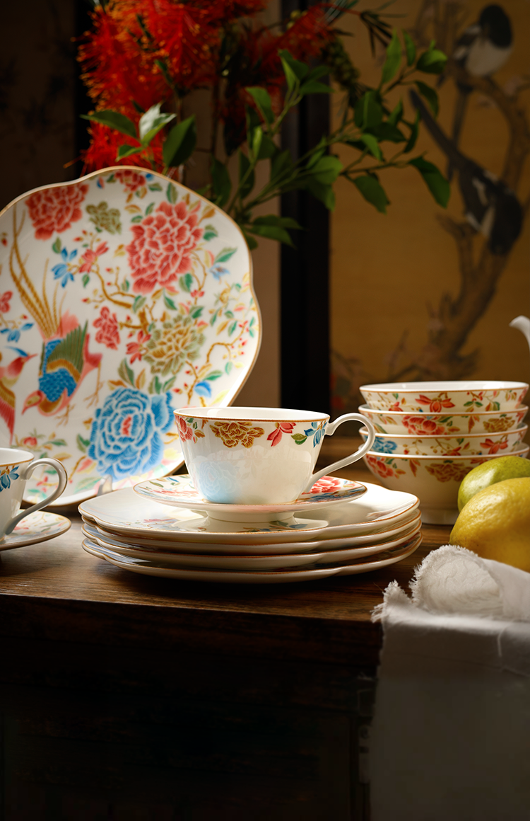 Luxury chinoiserie bone china dinnerware set with floral and bird motifs, including plates, teapot, and cups, arranged on an elegant table setting.