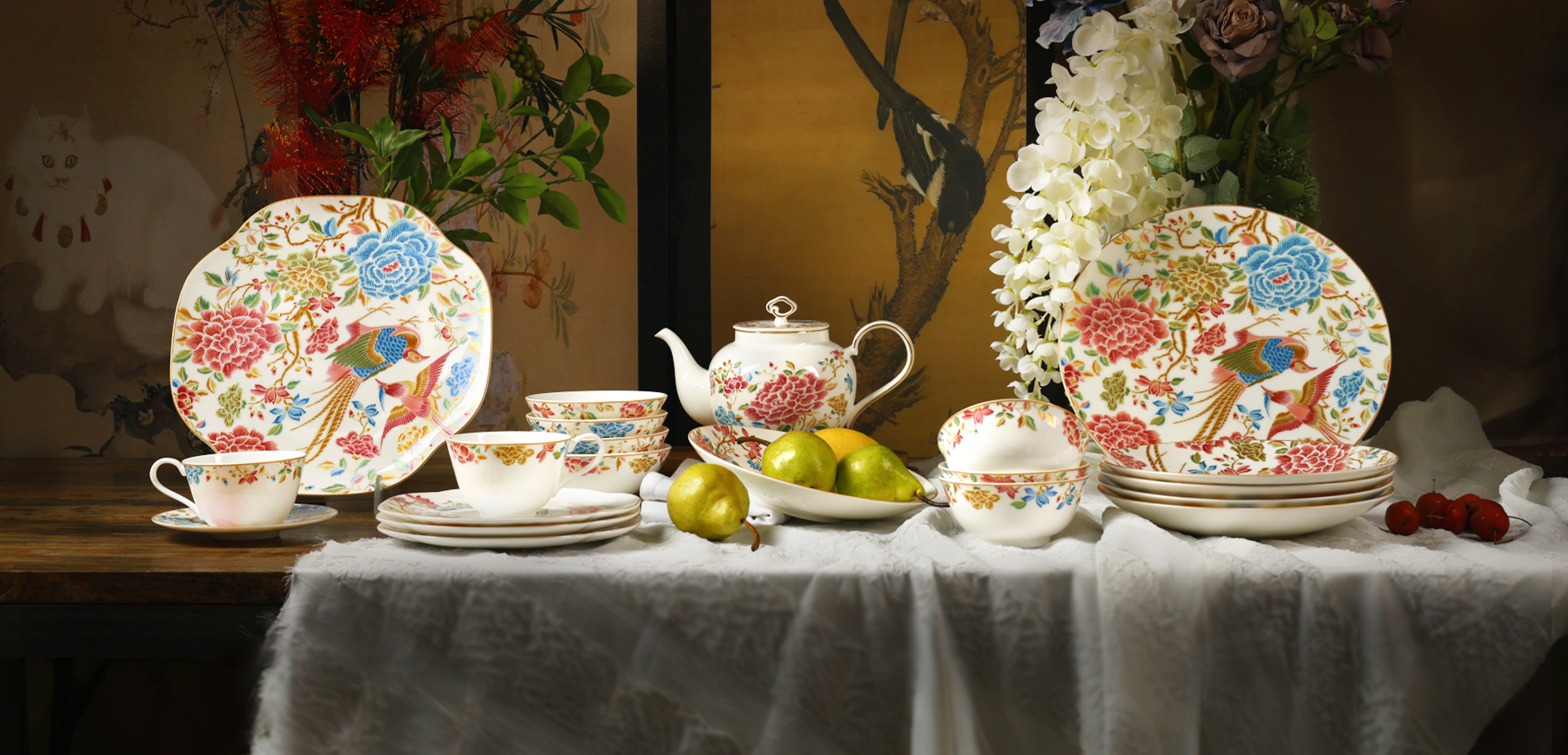 Luxury chinoiserie bone china dinnerware set with floral and bird motifs, including plates, teapot, and cups, arranged on an elegant table setting.