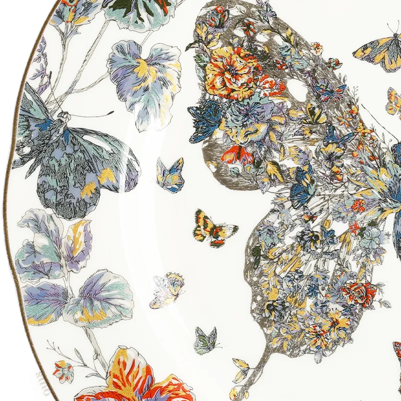 Close-up: Left butterfly wing and floral rim detail on bone china plate.