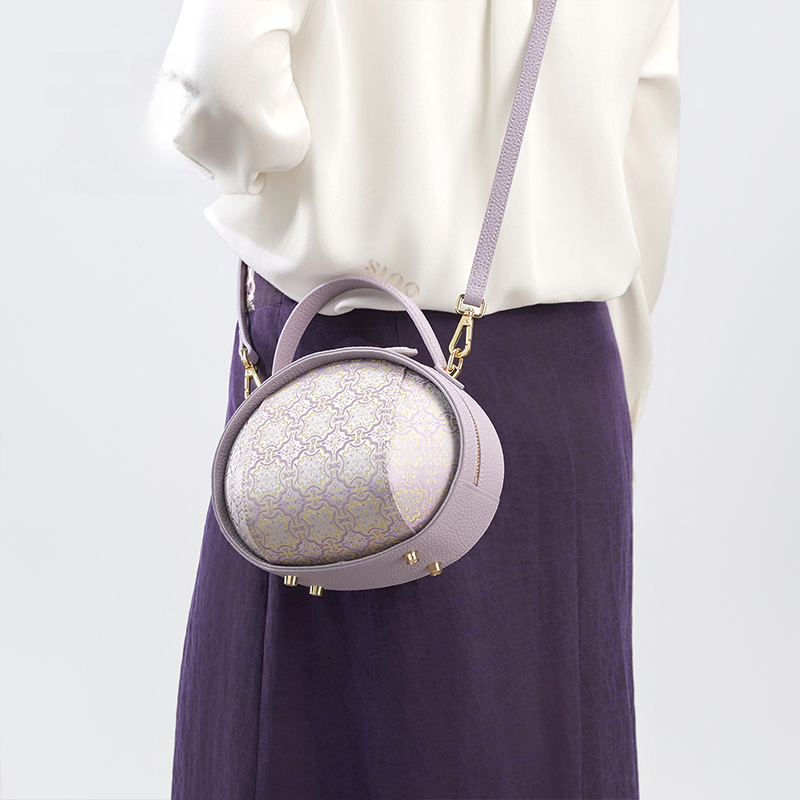 Model standing back with lavender Song Brocade handbag (Ding Sheng Pattern) crossbody.