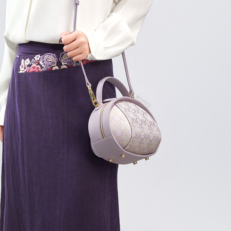 Model standing right with lavender Song Brocade handbag (Ding Sheng Pattern) single-shoulder.