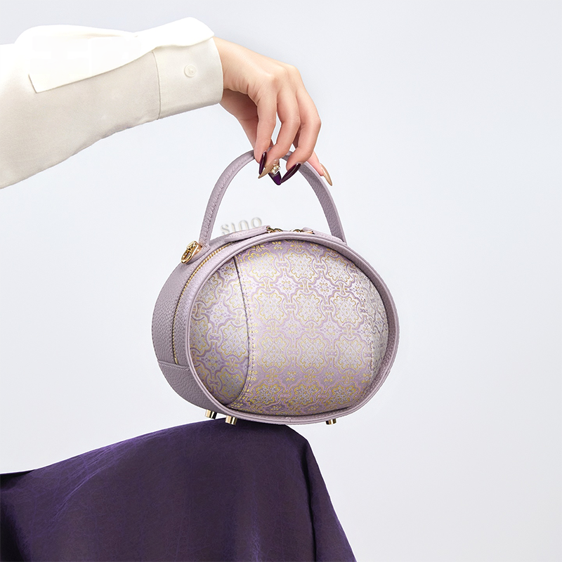 Model seated with lavender Song Brocade handbag (Ding Sheng Pattern) handheld on knee.