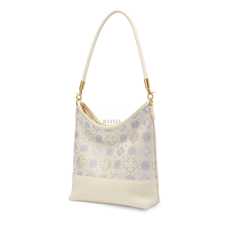 Angled view of the Shu Brocade Persimmon Calyx leather shoulder bag with ivory trim and gold-tone hardware.