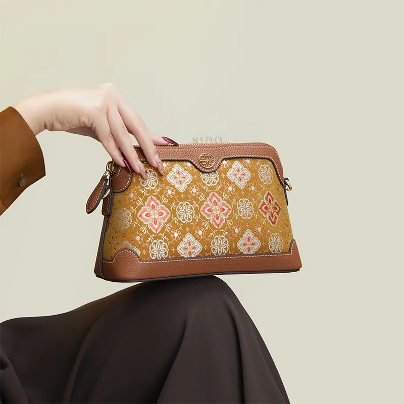 Model seated with the Persimmon Calyx Motif clutch purse placed on the knees.