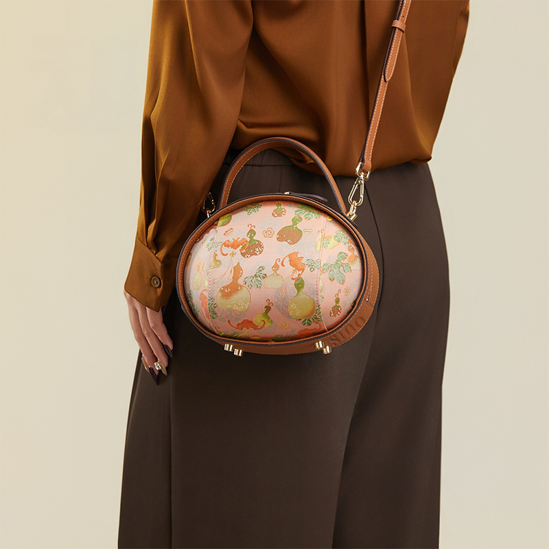 Model standing back with brown Song Brocade handbag (Gourd Pattern) crossbody.