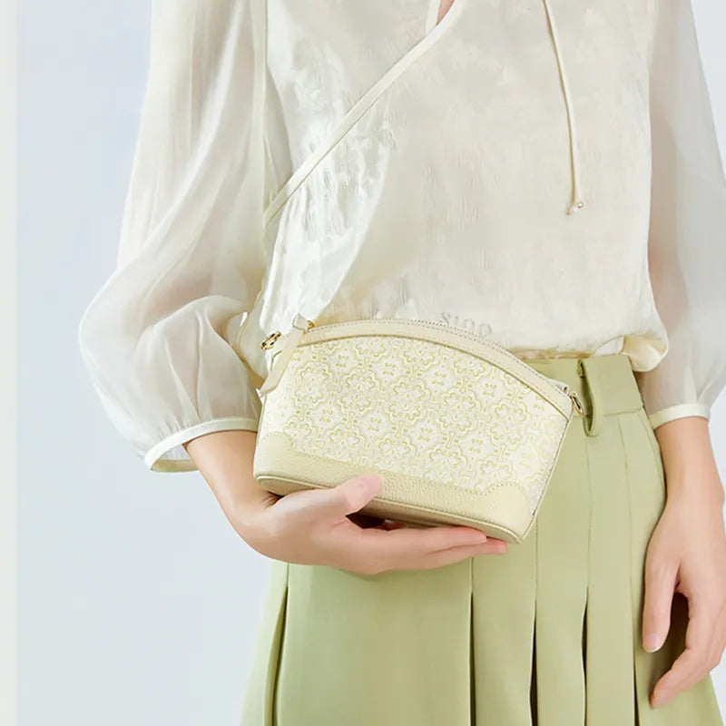 Model cradling clutch bag in right hand, showcase hold style.