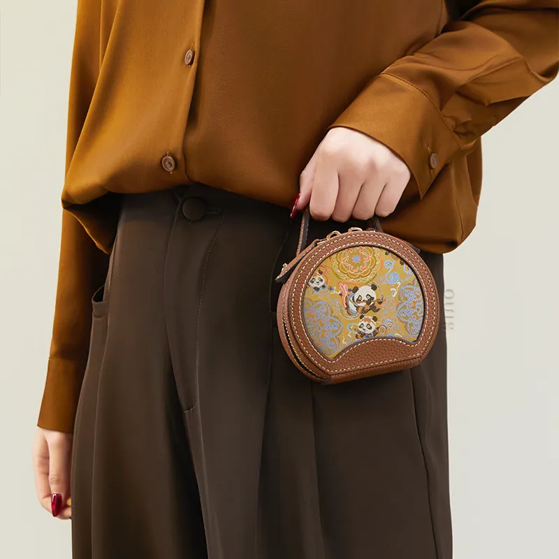 Model standing sideways lifting the Joyful Panda mini round bag by hand.