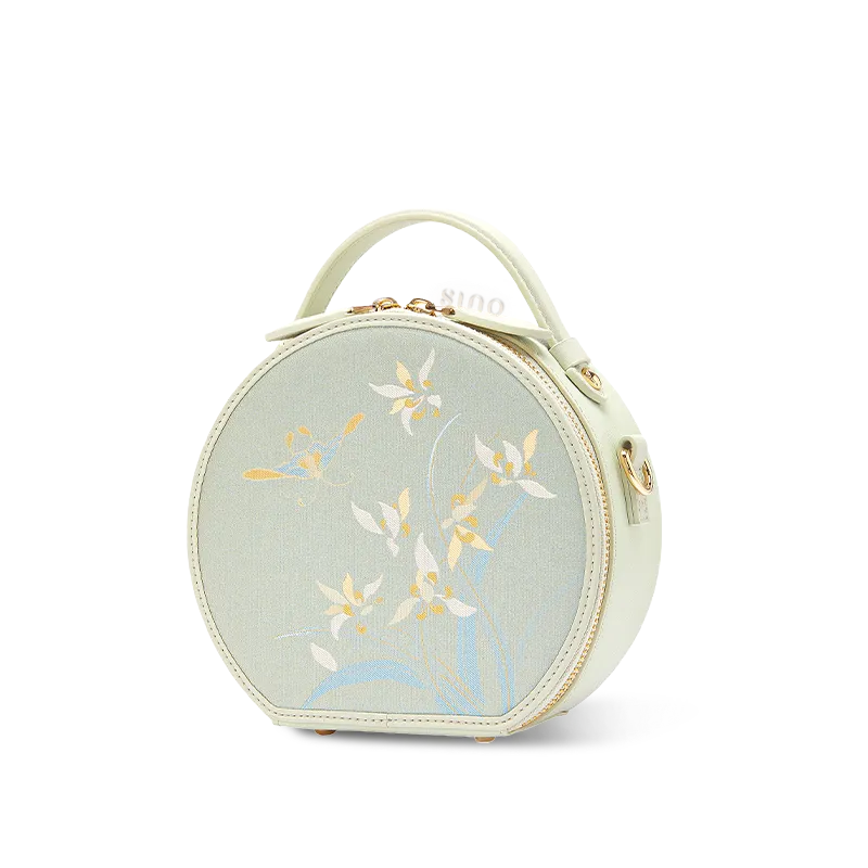 Side view of Chinoiserie Luxury Song Brocade Phalaenopsis Orchid Round Bag on white background.