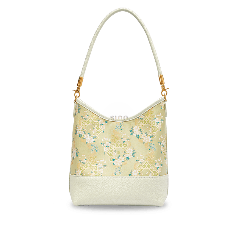 Front view of the Ruyi Blossom Song Brocade leather shoulder bag with ivory floral motifs on a soft green background.