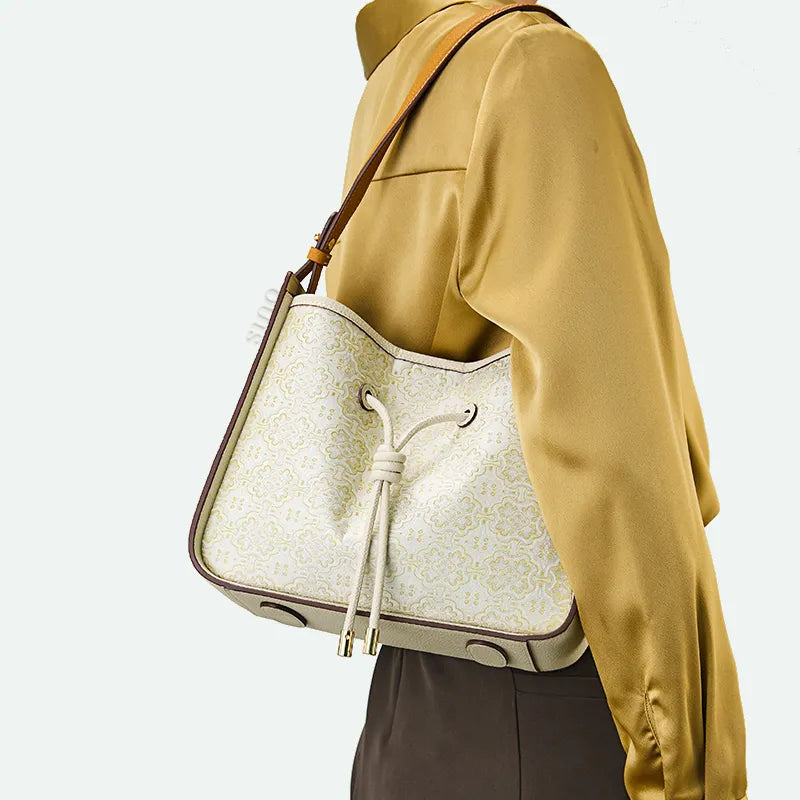 Short-strap shoulder carry at chest height with brocade bag.