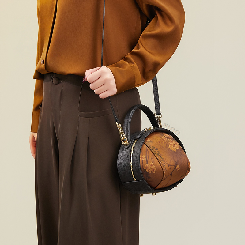 Model standing right with black Xiangyunsha handbag (Plum Blossom Print) over one shoulder.