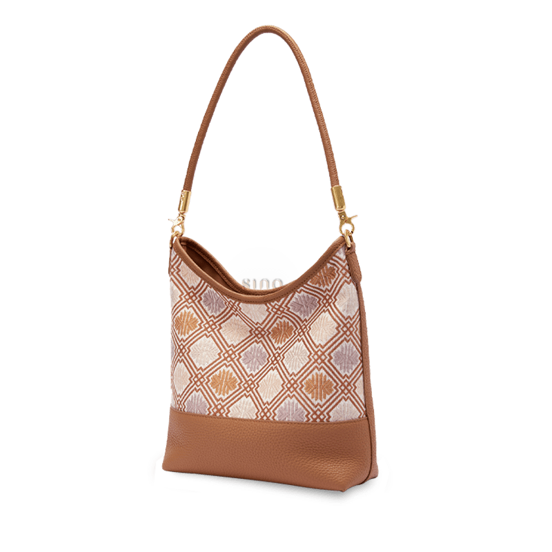 Angled view of the Zhuang Brocade Chrysanthemum Meander leather shoulder bag with warm brown leather and gold-tone hardware.