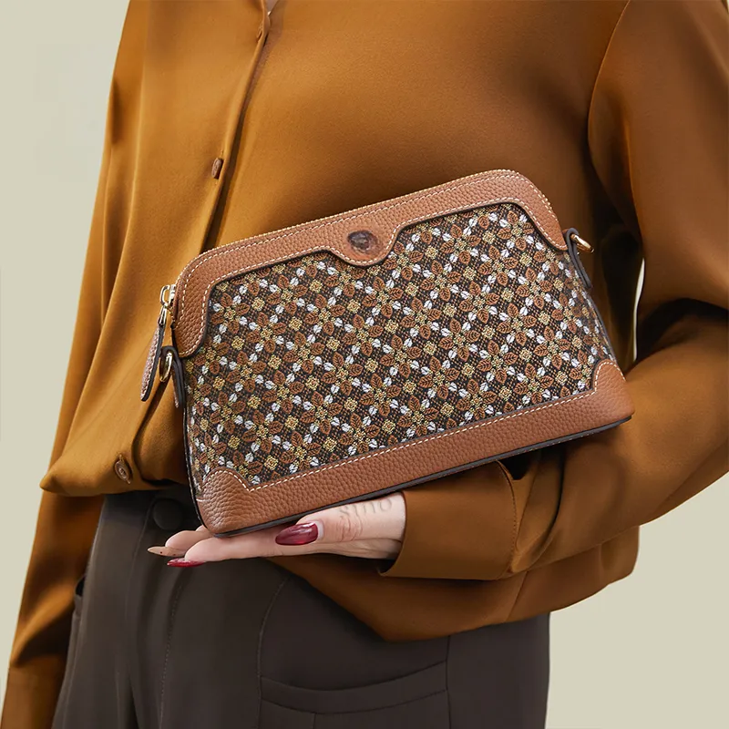 Model standing sideways holding the Osmanthus Motif clutch bag with one hand angled downward.