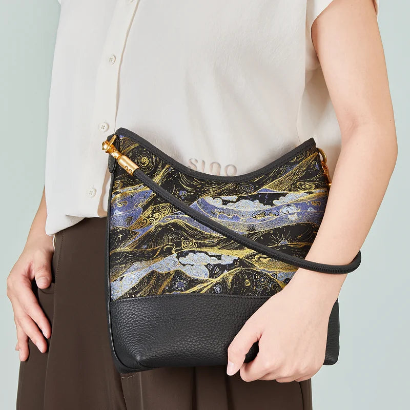 Model holding a Chinoiserie Moonlit Splendor shoulder bag crafted from Song Brocade and black leather.