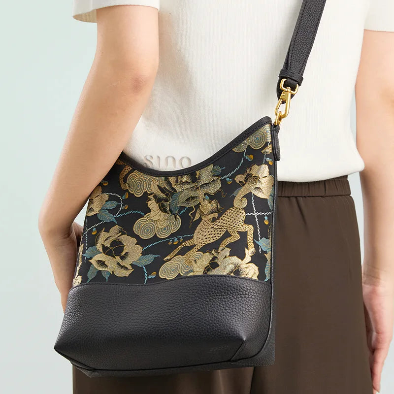 Model wearing the Chinoiserie Black Gold Qilin Peony Song Brocade bag with an adjustable leather strap.
