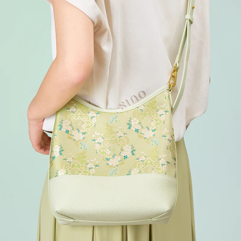Back view of a model wearing the Chinoiserie Ruyi Blossom Song Brocade shoulder bag with an adjustable strap.