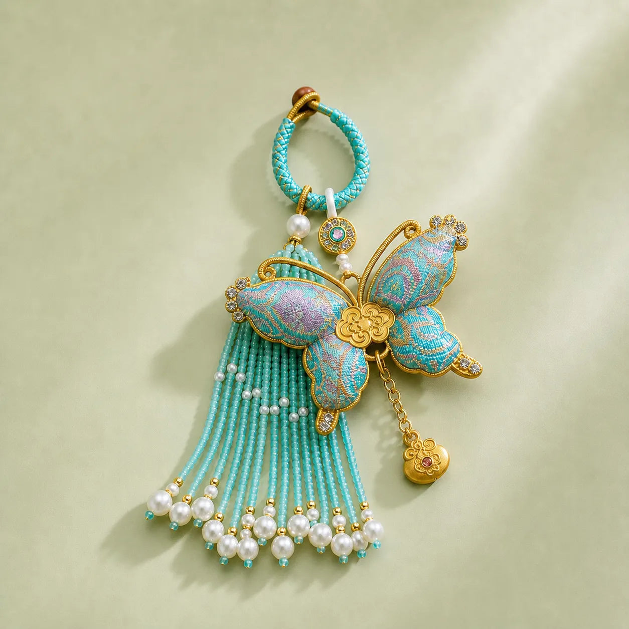 Turquoise Song Brocade butterfly pearl tassel bag charm with gold-tone trim, pearl-beaded tassels, and an ornate butterfly motif.