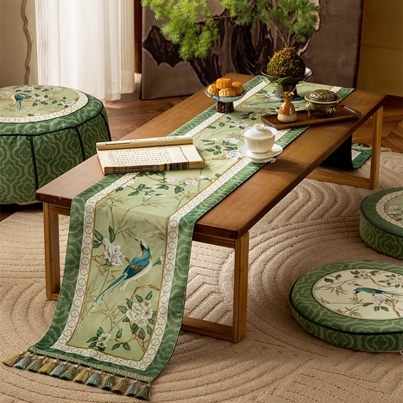 Chinoiserie vintage jade green long table runner with tassel fringe laid across a table with Chinese tea snacks, tea bowls, and Chinese books.