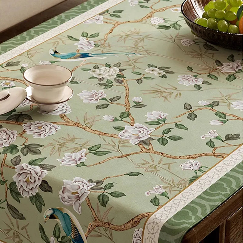Close-up of floral and bird pattern on chinoiserie vintage jade green tablecloth.