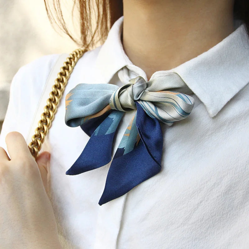 Woman wearing the Cloud & Water mulberry silk twilly tied as a neck bow, showing its elegant drape and refined print.
