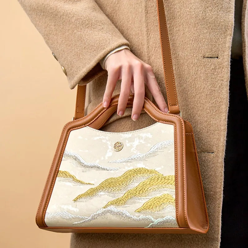 Model carrying a handmade silk and leather Cloud Mountain embroidery top handle bag.