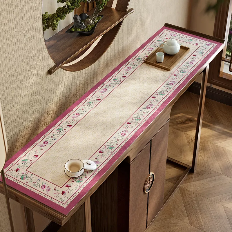 Coral pink leather cabinet top mat with floral border.