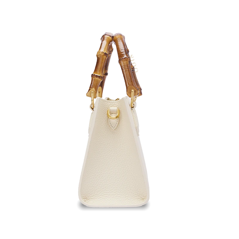 Angled view of Dayun Brocade floral handbag highlighting natural bamboo handle, leather side panels, and traditional textile craftsmanship.