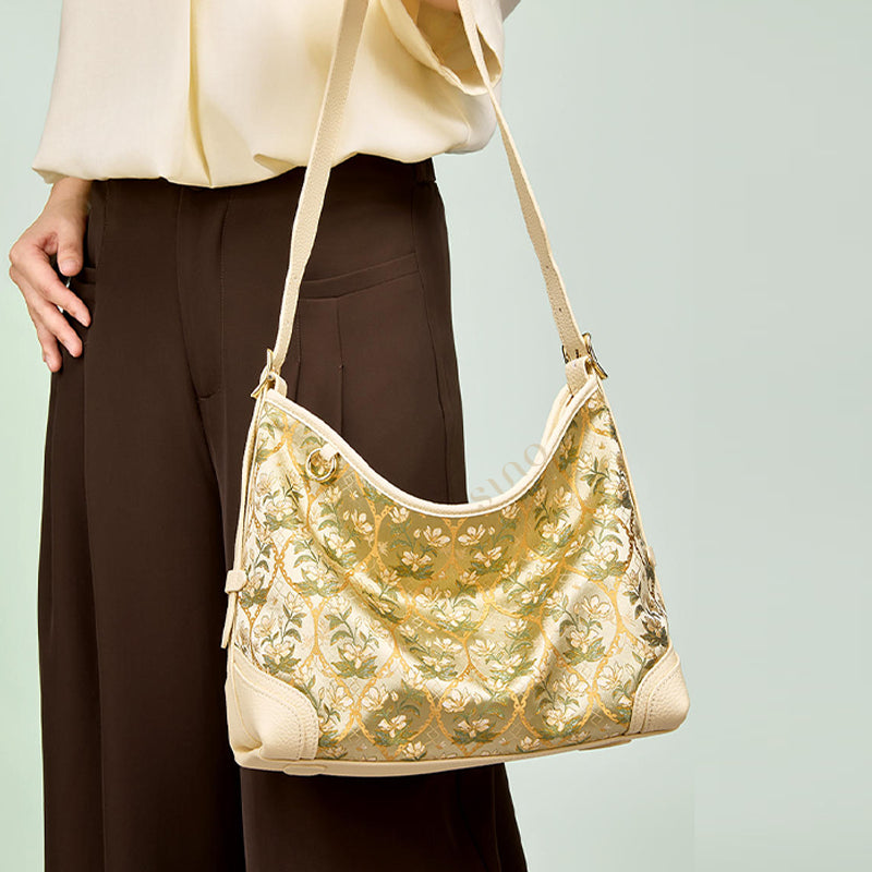 Model carrying the Chinoiserie Dayun Brocade Verdant Floral Leather Crossbody Bag with soft cream leather and floral brocade details.
