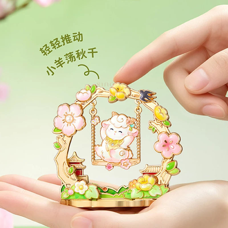 Hand holding a floral Year of the Goat fridge magnet featuring a smiling sheep on a swing, colorful blossoms, and traditional Chinese-inspired details.