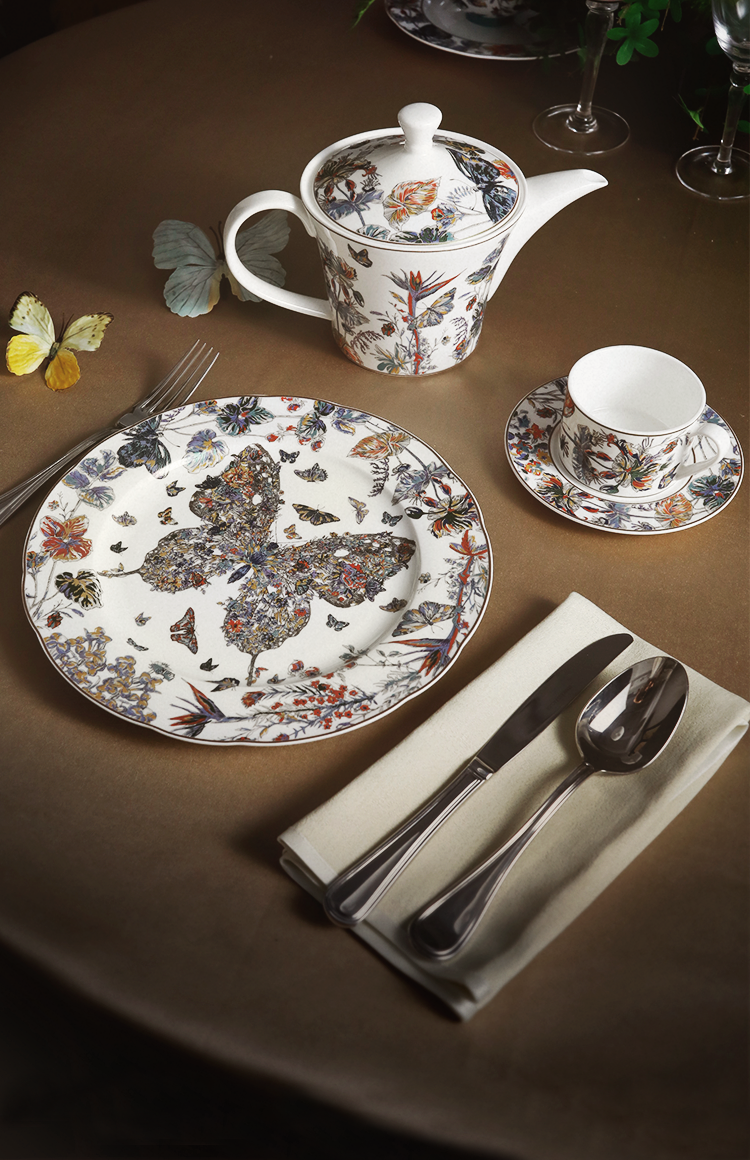 Luxurious table setting featuring our Golden Butterfly Dance series bone china—delicate butterfly and floral patterns adorn plates, a teapot, and cups, accented by fresh greenery and blooms.