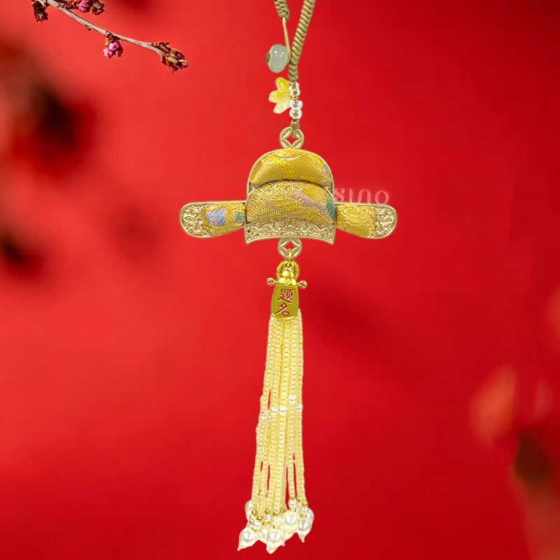 Golden Nanjing Yunjin brocade Imperial Scholar Hat long tassel bag charm displayed against a red background with ornate trim and a long beaded tassel.