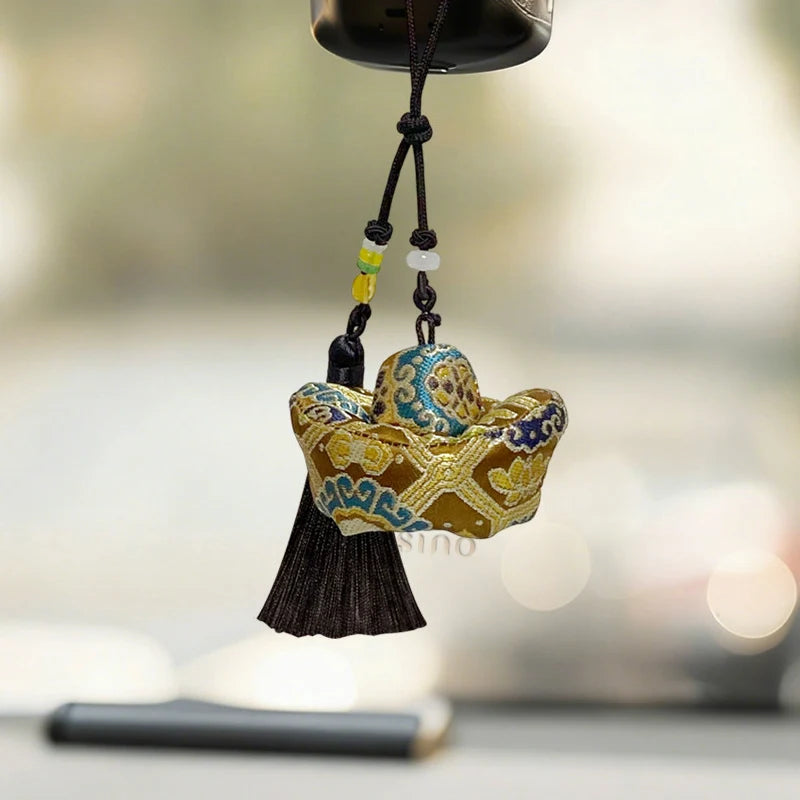 Golden Yunjin brocade Yuanbao long tassel bag charm hanging inside a car with a dark cord, beaded accents, and a flowing tassel.