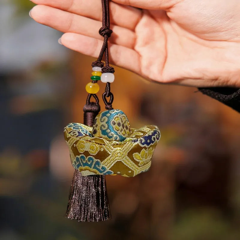 Handheld golden Yunjin brocade Yuanbao long tassel bag charm with a dark cord, decorative beads, and a silky tassel.