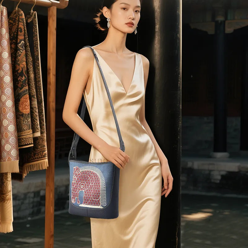 Asian woman wearing crossbody bag diagonally, horse embroidery detail visibleoverlay.