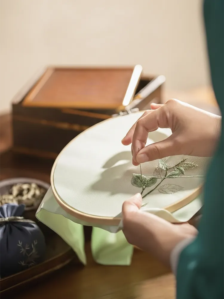 Artisan hand-embroidering floral design, honoring Chinese cultural heritage.