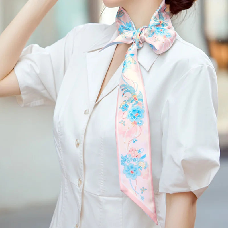 Pink and blue Jeweled Phoenix & Peony Mulberry Silk Twilly styled as a bow neck scarf with a white shirt.