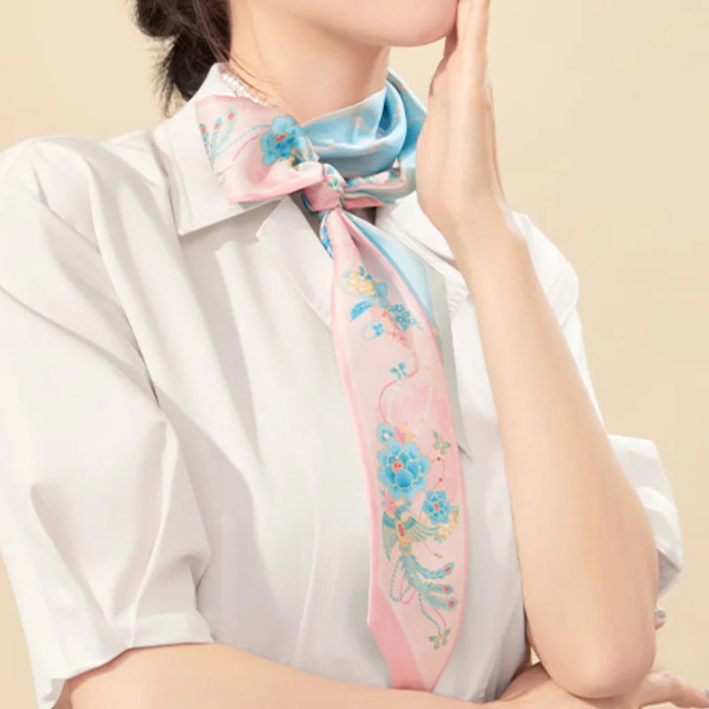 Woman wearing the pink Jeweled Phoenix & Peony Mulberry Silk Twilly as an elegant long neck scarf.