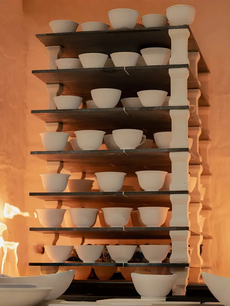 White ceramic bowls and cups on kiln shelves during firing—cover for ceramic firing guide blog.
