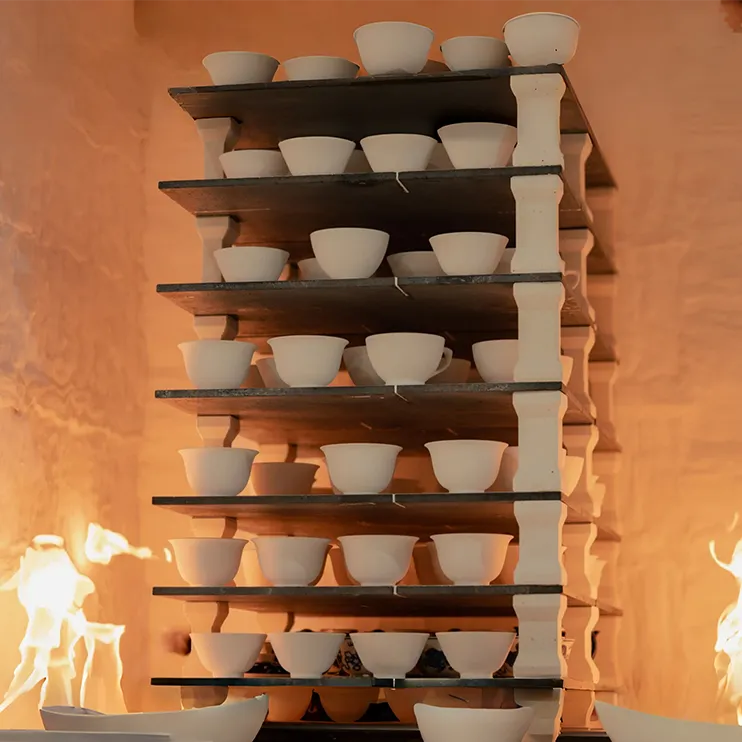 White ceramic bowls and cups on kiln shelves during firing—cover for ceramic firing guide blog.